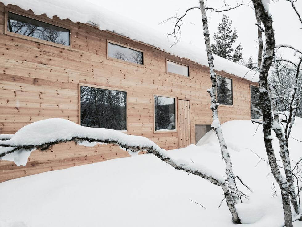 Fasaden på fjällstugan med snö